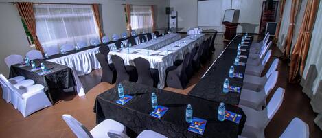 A conference room with a long table, white chairs, and water bottles.