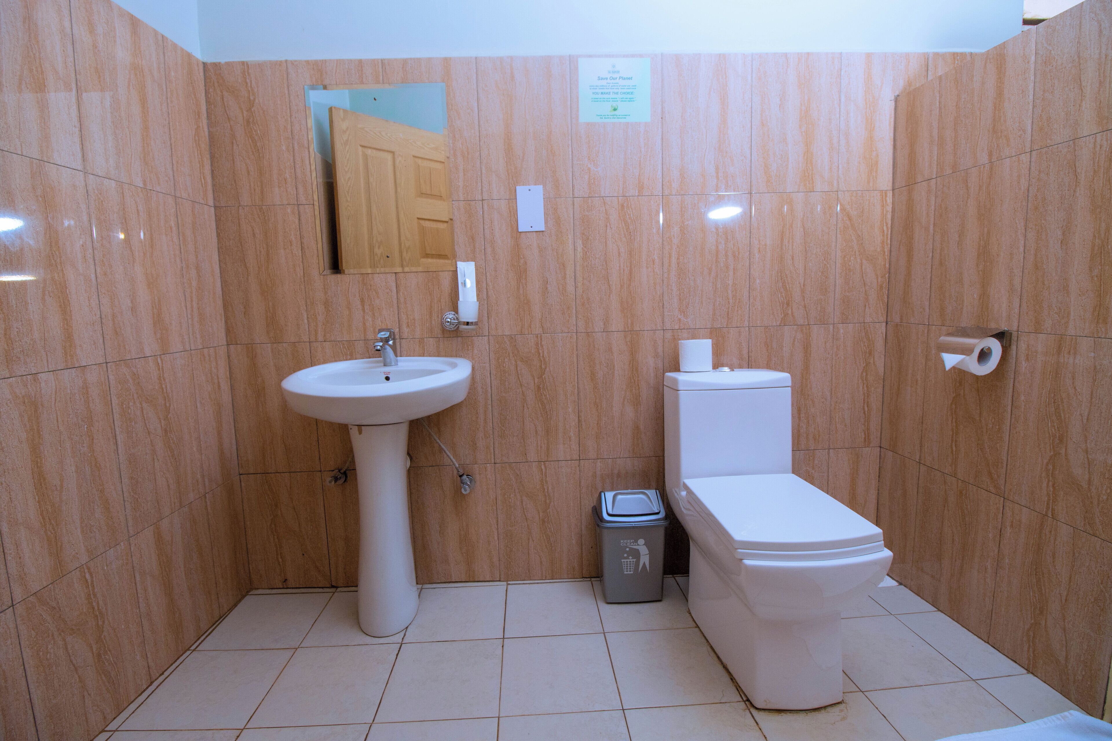 Un baño con lavamanos, inodoro y un cubo de basura.