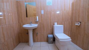 Un baño con lavamanos, inodoro y un cubo de basura.