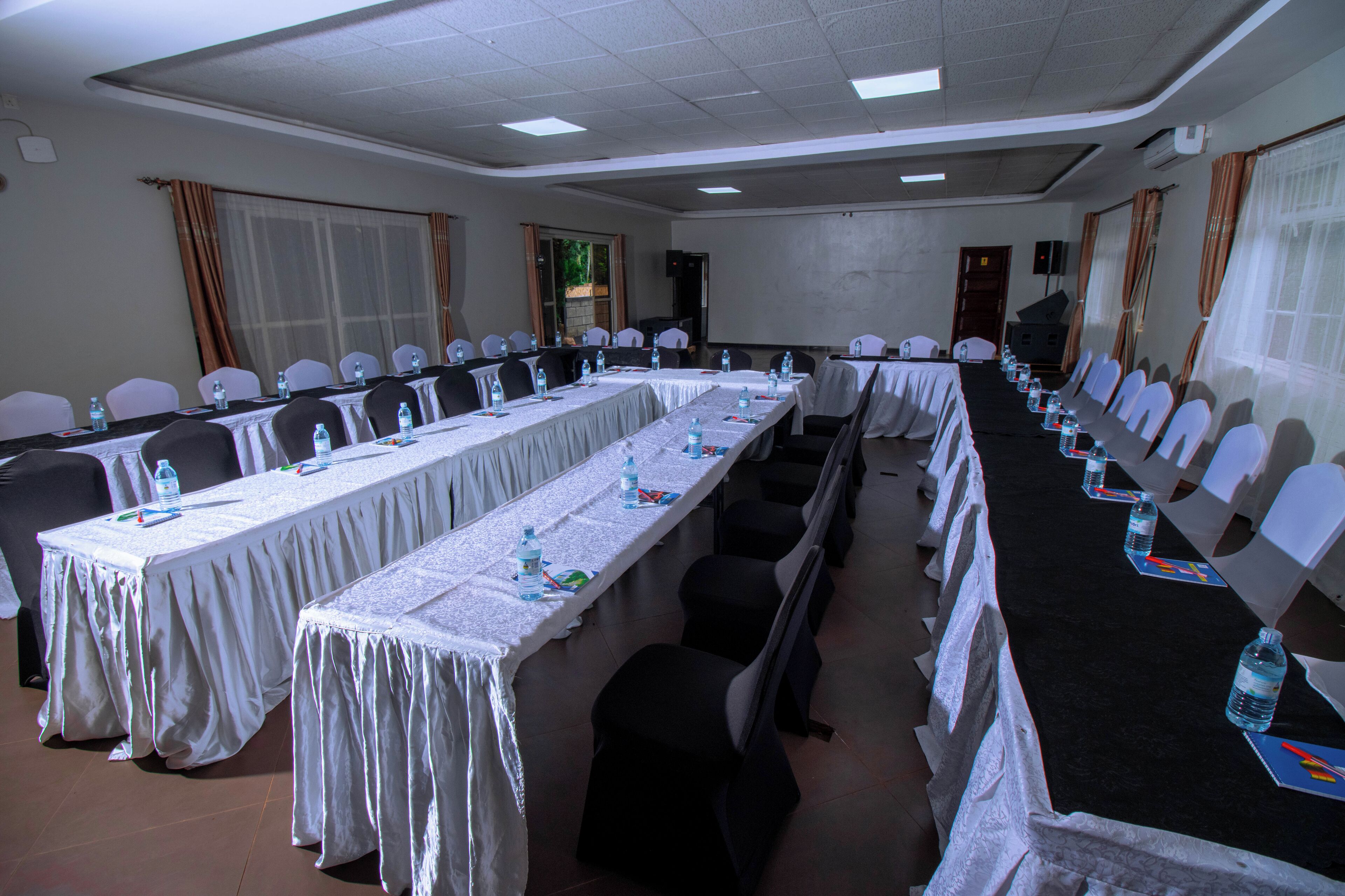A conference room with long tables, chairs, and water bottles.
