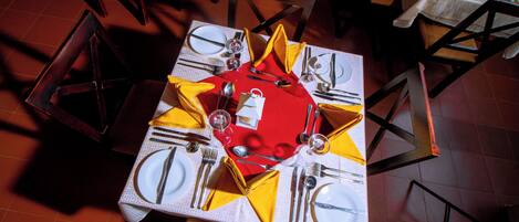 A dining table set with multiple chairs, each with a yellow napkin and a white tablecloth.
