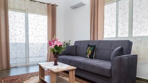 En stue med en grå sofa, et lille træ sofabord og et gulvtæppe med et mønster.