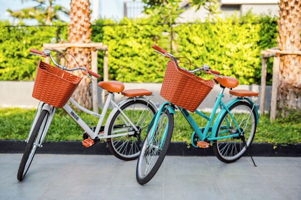 Dos bicicletas aparcadas una al lado de la otra, cada una con una cesta de mimbre en la parte delantera.
