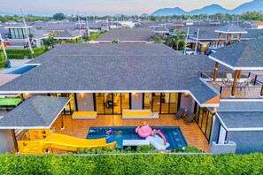 Zona residencial con casas modernas, una piscina con sillones de descanso y un tobogán.