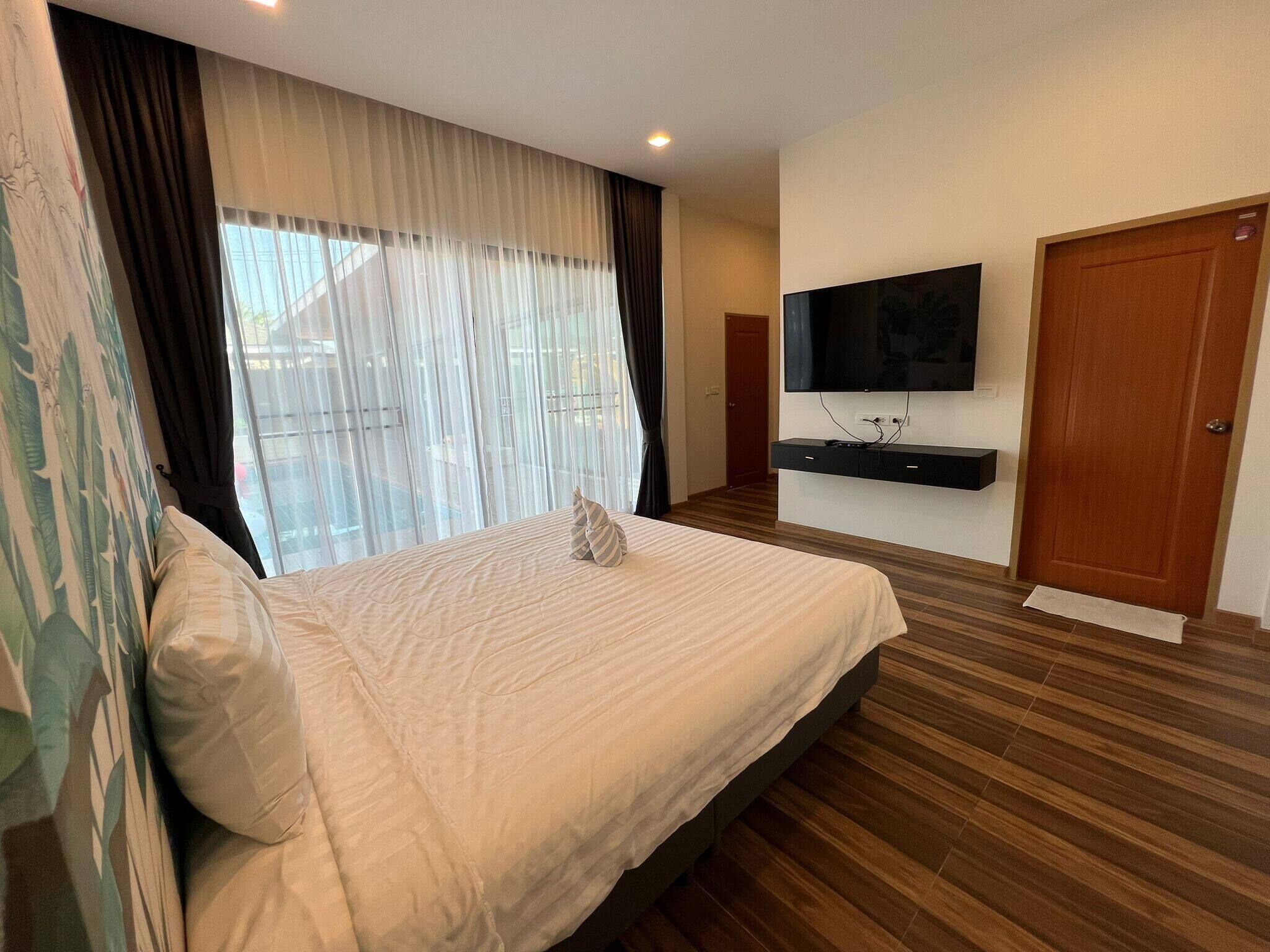 Habitación de hotel con una cama grande, un televisor de pantalla plana montado en la pared y suelo de madera.