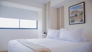 A hotel room with a large bed, a window, and a framed picture on the wall. - w* | Alluring 2BR w/ Balcony in Barranco (Barranco)