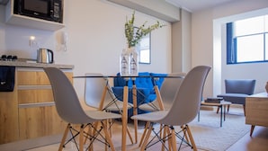 A modern kitchen with a microwave, a coffee maker, and a vase with plants. There is a dining table with chairs and a blue sofa in the background. - w* | Alluring 2BR w/ Balcony in Barranco (Barranco)