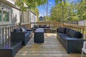 Een terras buiten met een zithoek en een bijzettafeltje.