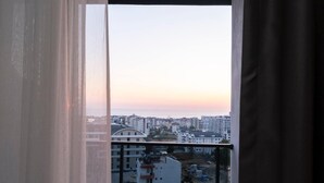 A view from a window overlooking a cityscape at sunset.