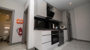 A modern kitchen with white cabinetry, a black countertop, and stainless steel appliances.