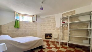 Une pièce avec un lit, une chaise, une étagère et un sol à carreaux.