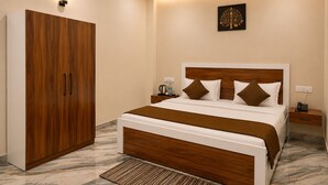 A bedroom with a bed, wooden wardrobe, bedside tables, and a ceiling fan. - Shri Raghav Palace Hotel Ayodhya (Faizabad)
