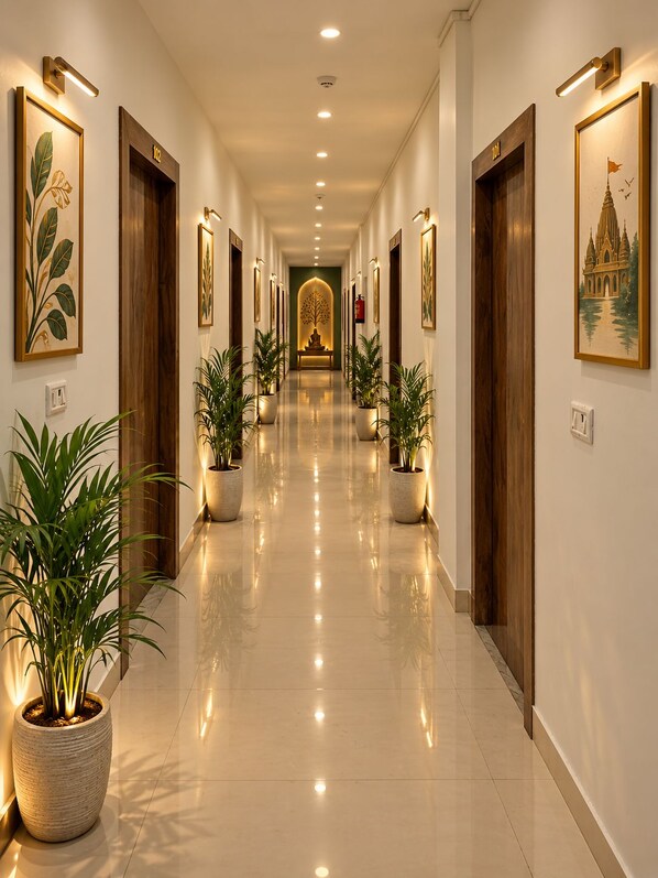 Un pasillo de hotel con puertas de madera, plantas en macetas y cuadros en las paredes.