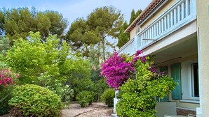 Un sendero en un jardín que lleva a un edificio con balcón y zona de estar al aire libre.
