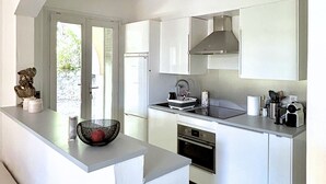 Una cocina moderna con armarios blancos, horno empotrado y un amplio ventanal que aporta luz natural.
