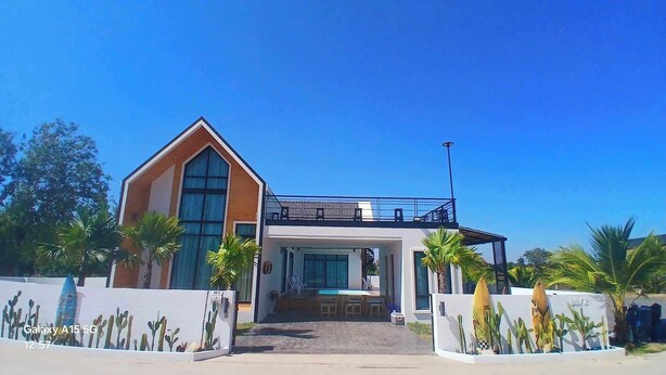 A modern two-story house with a large front porch, a balcony, and a garage.