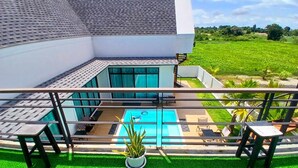 A modern house with a rooftop pool, a glass conservatory, and a view of a lush green field.