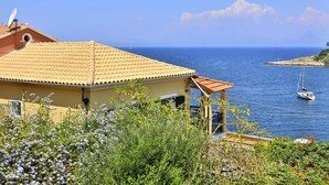 A coastal building with a tiled roof overlooking a calm sea. - Vostalo apartments by Kassiopi's Sea (Kassiopi)