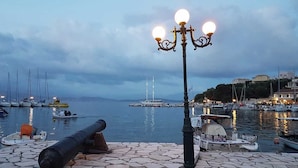 A harbor with boats, a lighthouse, and a stone-paved walkway. - Vostalo apartments by Kassiopi's Sea (Kassiopi)