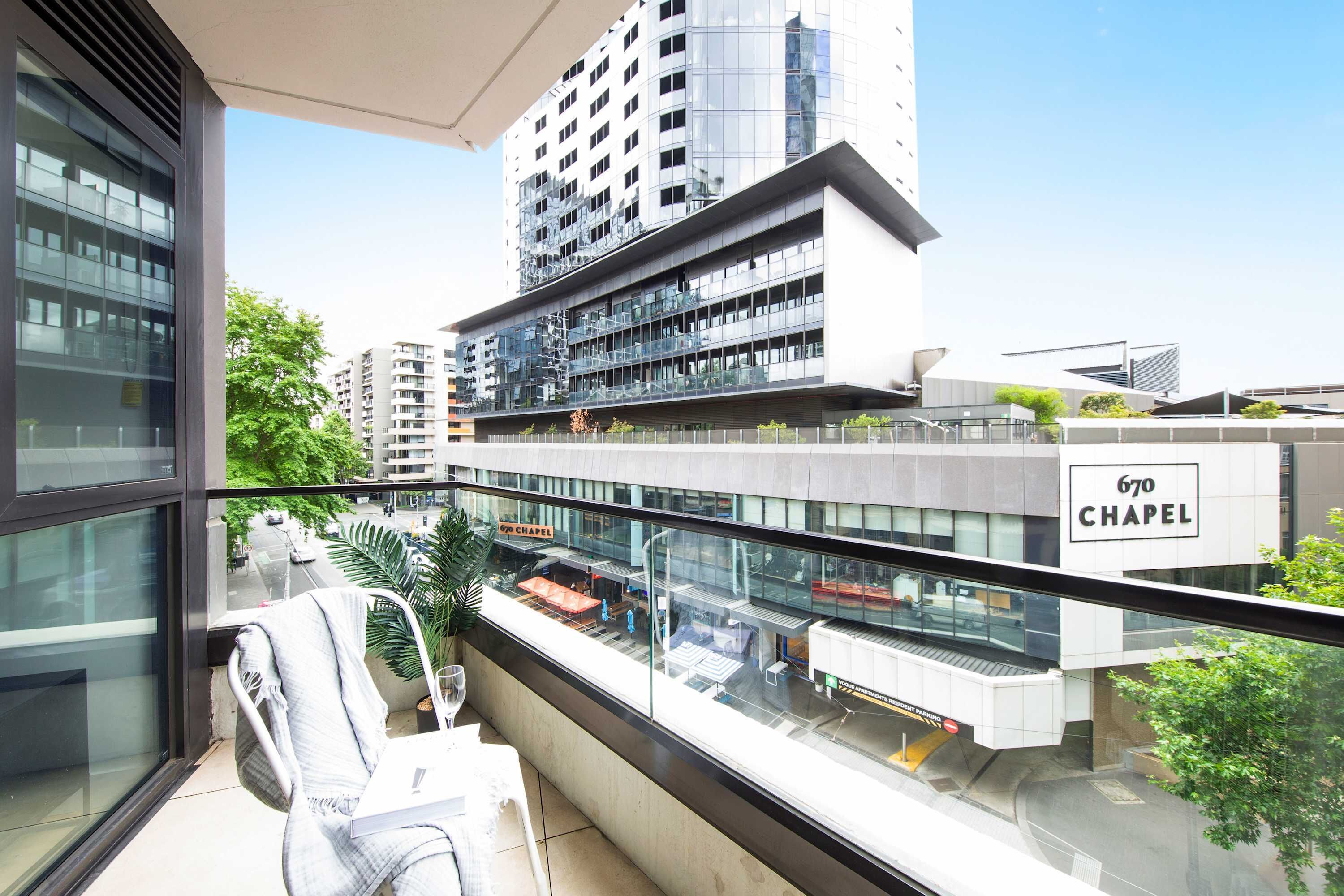 A modern building with a glass facade, a sign reading "670 CHAPEL," and a view of a street with cars and trees.