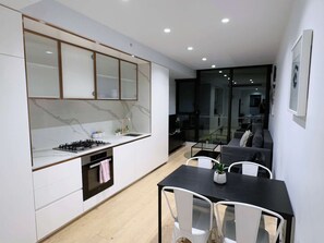 A modern kitchen with a built-in stove, oven, and a glass-fronted cabinet. - Bright & Modern 2BR Apt on Iconic Chapel Street (South Yarra)