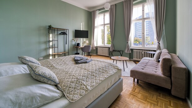 Habitación de hotel moderna con una cama grande, un sofá, un televisor y vistas a la ciudad.