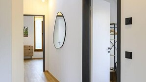 Een modern interieur met een houten vloer, een spiegel en een deur naar een andere kamer.