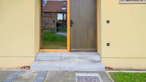 A modern building entrance with a glass door, a wooden door, and a small step leading up to the door. - Spreewald courtyard - south side with terrace (Unterspreewald)