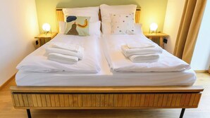 A double bed with white linens, two bedside tables with lamps, and a wooden headboard. - Spreewald courtyard - south side with terrace (Unterspreewald)