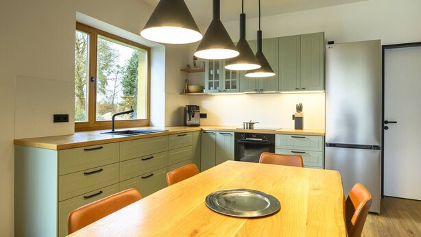 A modern kitchen with a wooden dining table, pendant lights, and a built-in oven. - Spreewald courtyard - south side with terrace (Unterspreewald)