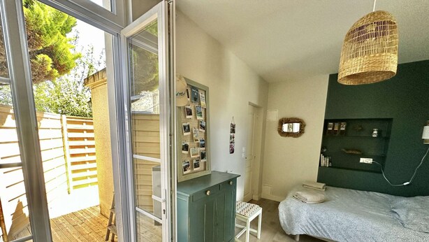 A bedroom with a bed, a dresser, a mirror, and a hanging light fixture.