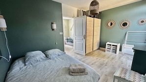 A bedroom with a bed, a wardrobe, a chair, and a hanging light fixture.