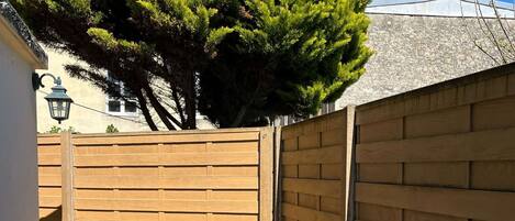 Un patio con mesa y sillas, una valla de madera y un árbol.