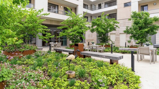 A courtyard with a bird sculpture, outdoor seating, and a building with multiple balconies. - Zenao Appart'hôtel Saint-Maur-des-Fossés (Saint-Maur-des-Fosses)