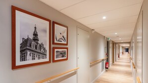 A corridor with framed pictures on the wall, wooden handrails, and a fire extinguisher. - Zenao Appart'hôtel Saint-Maur-des-Fossés (Saint-Maur-des-Fosses)
