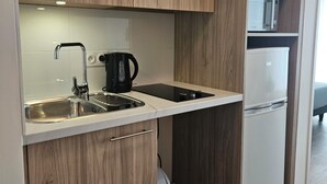 A modern kitchen with wooden cabinets, a stainless steel sink, a black coffee maker, and a white refrigerator. - Zenao Appart'hôtel Saint-Maur-des-Fossés (Saint-Maur-des-Fosses)