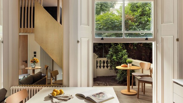 A modern interior with a dining area, a staircase, and a view of greenery outside. - FiveM Notting Hill (London)