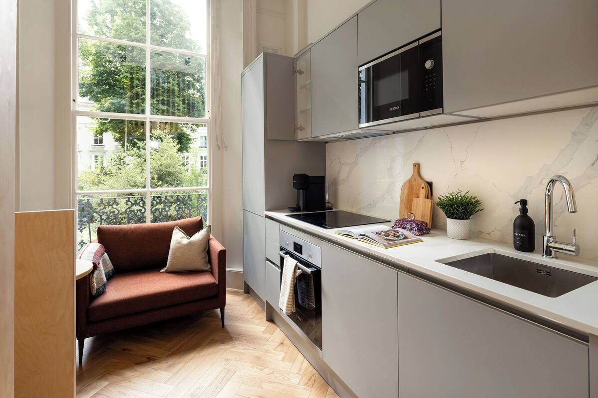 A modern kitchen with a built-in microwave, a sink, and a window overlooking a cityscape.