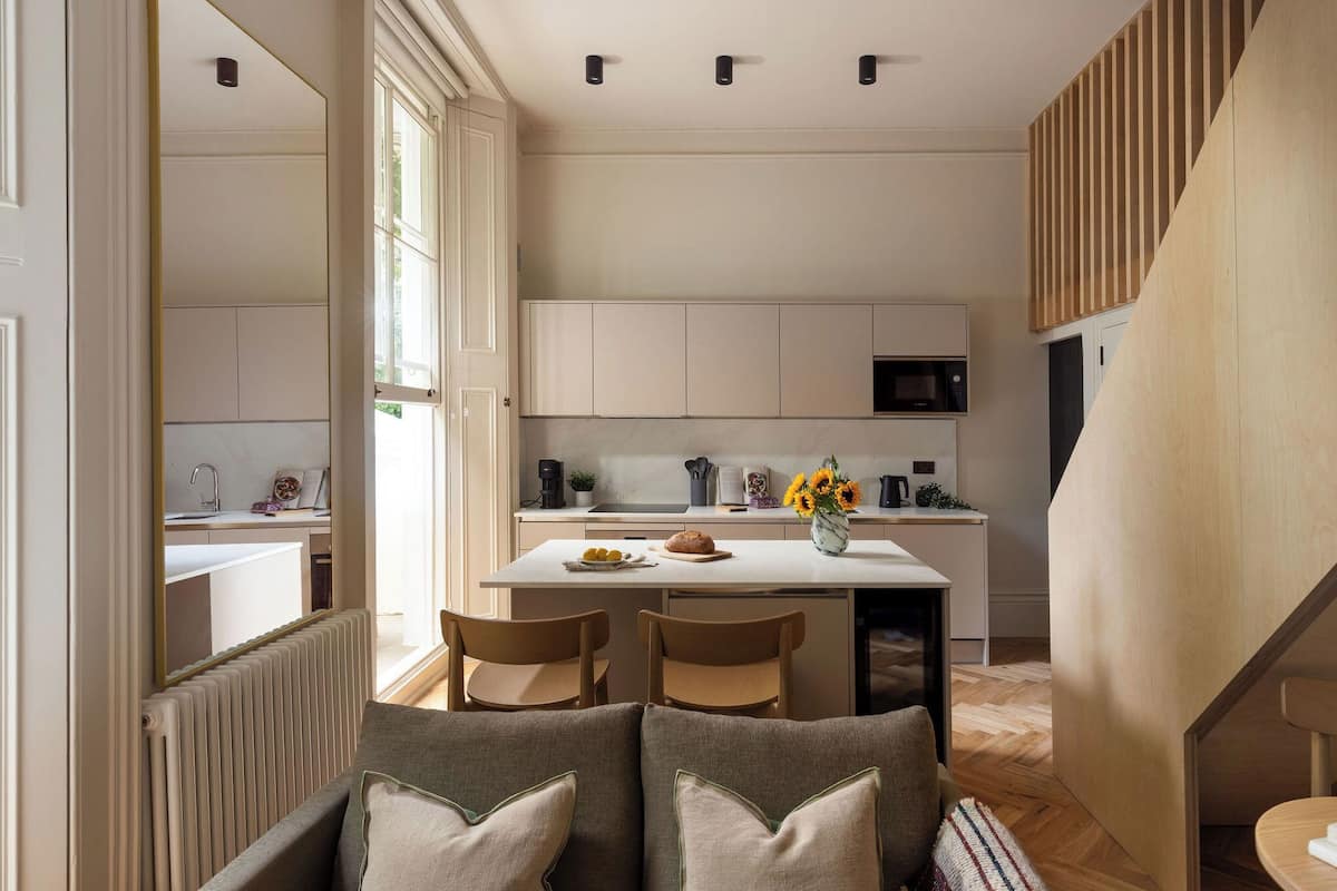 A modern kitchen with white cabinets, a central island, and a dining area with two chairs.