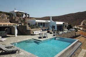 Une villa moderne dotée d’une piscine, d’un espace salon extérieur et d’un escalier en pierre.
