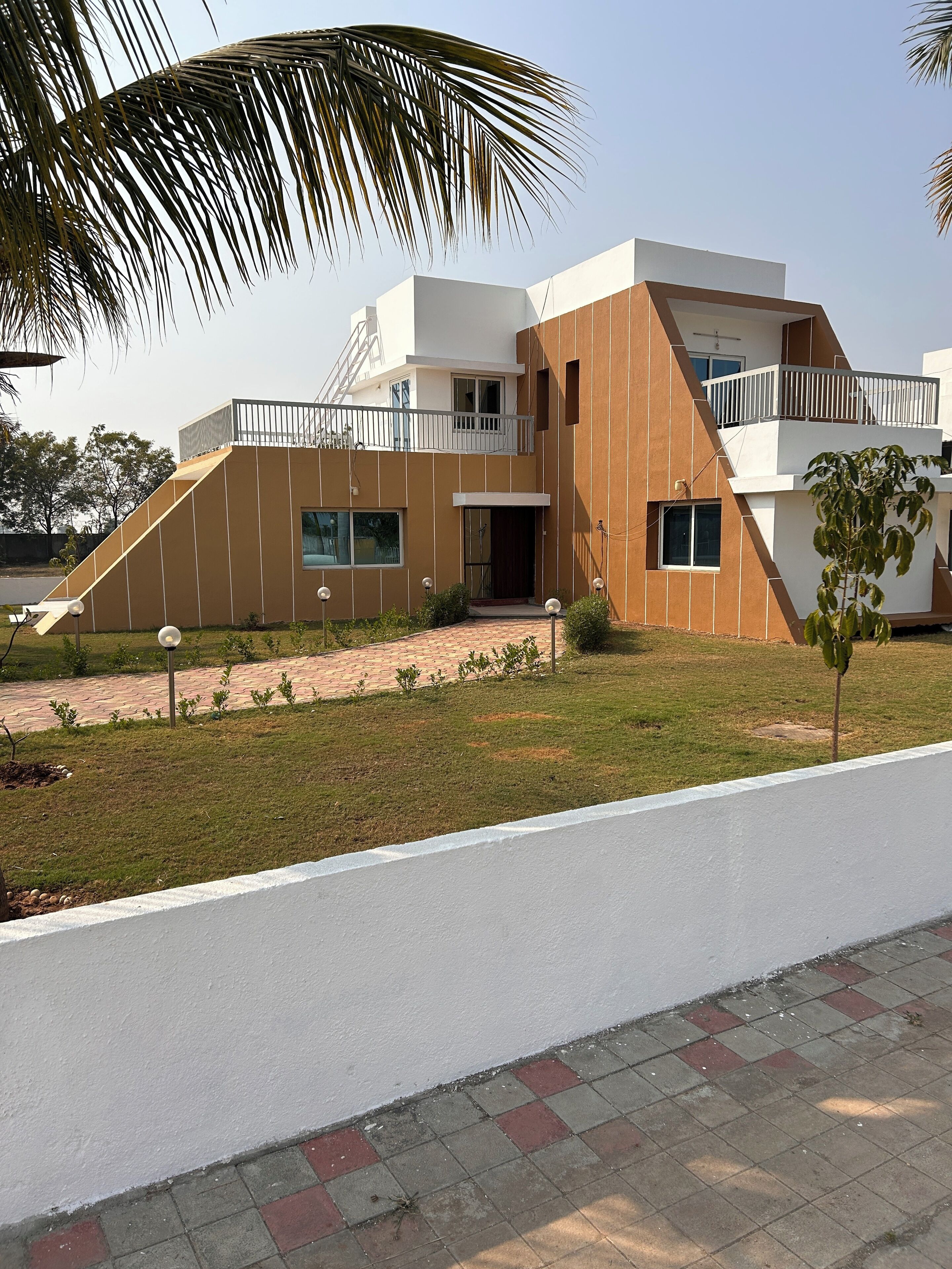 A modern two-story building with a flat roof, large windows, and a balcony.