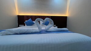 A hotel room with a neatly made bed, a heart-shaped towel arrangement, and a modern headboard. - hotel surya grand (Mumbai)