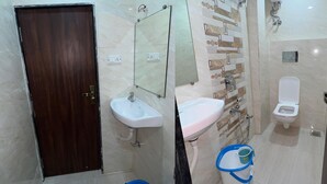 A bathroom with two sinks, a toilet, and a mirror. There are two blue buckets on the floor. - hotel surya grand (Mumbai)