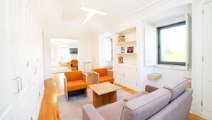 Un intérieur moderne avec un canapé, des fauteuils, une petite table et une bibliothèque.