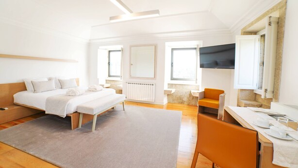 Une chambre d’hôtel moderne équipée d’un lit, d’un bureau, d’une chaise, d’une télévision et d’une grande fenêtre.