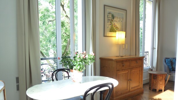 Un coin repas avec une table et des chaises, un buffet en bois et un tableau accroché au mur.