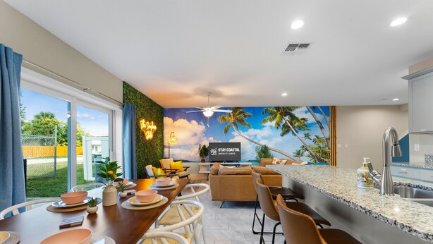Una cocina moderna con una isla grande, taburetes de bar y un comedor con vistas al exterior.