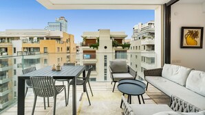 A balcony with a dining table, chairs, and a sofa.