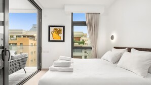 A modern hotel room with a large bed, a balcony with a chair, and a city view.