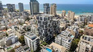 A high-rise urban area with modern buildings, a beach, and a clear view of the sea.